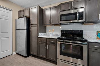 A kitchen with brown cabinet storage and stainless-steel appliances.